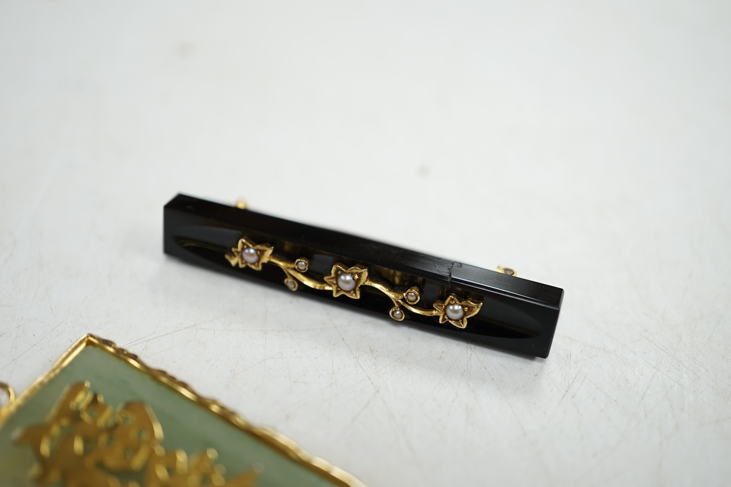 A late Victorian gold mounted black onyx and pearl bar brooch, and a Chinese yellow metal mounted jadeite pendant. Condition - fair